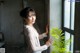 A woman standing in front of a window next to a plant.