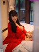 A woman in a red dress sitting on a bed.