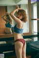 A woman in a blue bra and red panties standing in front of a mirror.