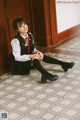 A woman sitting on the floor in a school uniform.