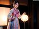 A woman in a kimono holding a lantern in front of a window.