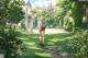 A woman walking through a lush green park with a backpack.