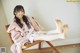 A woman sitting on a wooden chair with her feet up.