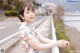 A woman in a floral dress leaning on a railing.