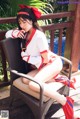 A woman in a red and white outfit sitting on a chair.