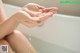 A woman is washing her hands in a bathtub.